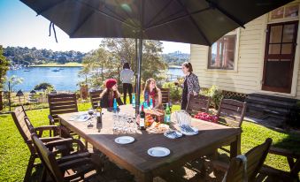 a group of people gathered around a large dining table in a backyard , enjoying a meal together at Cockatoo Island Accommodation