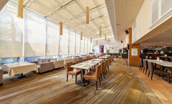 a large , modern restaurant with wooden tables and chairs , white walls , and a panoramic view of the ocean at Swan Hotel