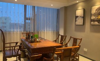 A room with spacious windows and a dining table enclosed within it, along with chairs in the living area at Mumian Hotel (Guangzhou Baiyun International Airport)