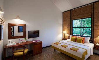 a hotel room with a bed , desk , and tv , as well as a window with wooden blinds at Habarana Village by Cinnamon