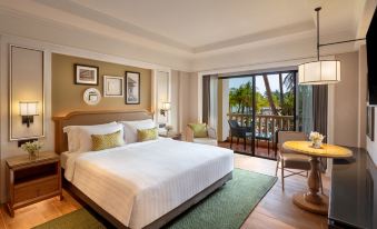 a large bedroom with a king - sized bed , a tv mounted on the wall , and a door leading to a balcony at Dusit Thani Hua Hin
