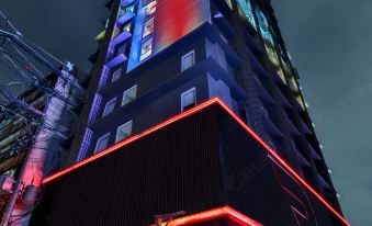 a tall building with red and blue lights on it , illuminated by a spotlight at night at Red Planet Manila Bay