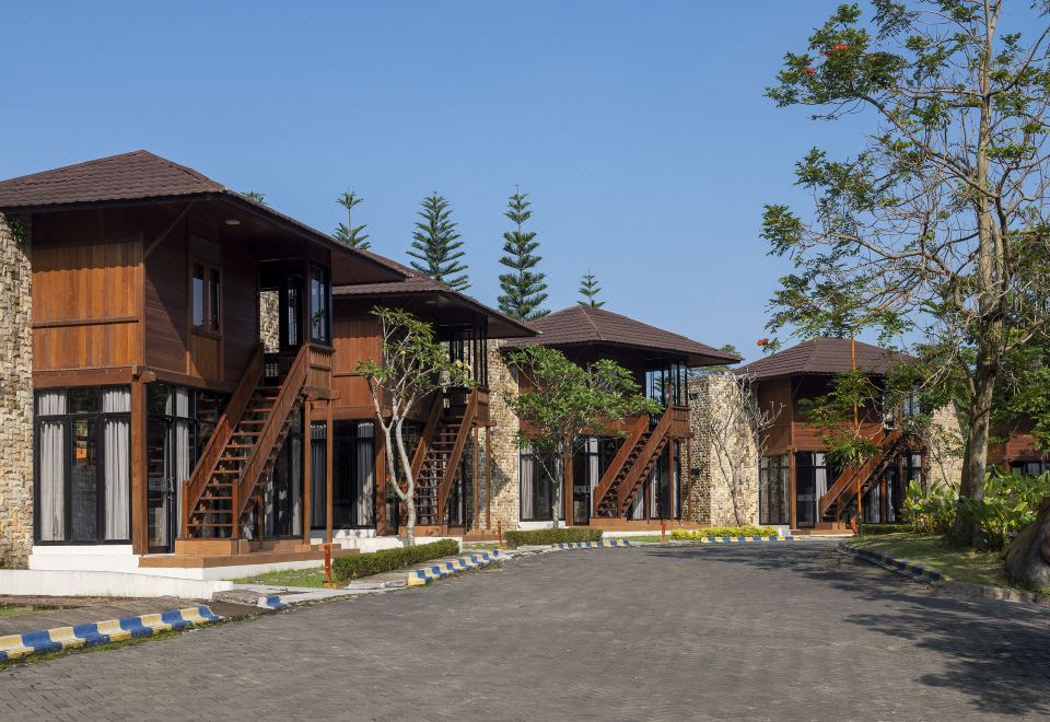 a row of wooden houses with stairs leading up to them , surrounded by trees and grass at Jsi Resort