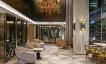 There is a lobby with chairs and tables in the middle, adjacent to an entrance at HOMM Sukhumvit34 Bangkok - a brand of Banyan Group
