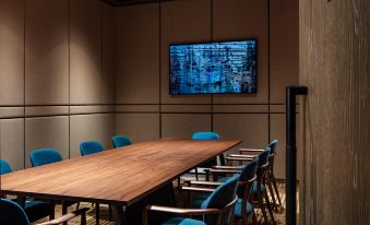 The conference room features blue chairs and a wooden table in the center, along with an empty space at The Hari Hong Kong