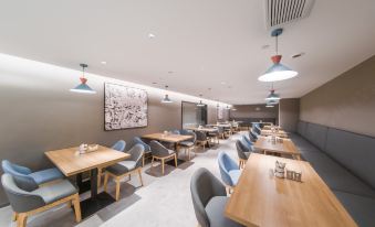 The restaurant features an open concept dining room with tables and chairs in the middle at Home·NEO Hotel (Guangzhou Exhibition Center Pazhou Metro Station)