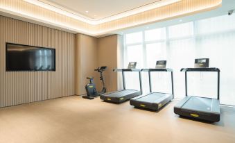 There is a spacious room with an exercise bike and other equipment in the living area adjacent to it at All Seasons Hotel (Guangzhou Tianhe Sports Center Branch)