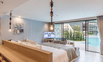 a modern bedroom with a king - sized bed , a flat - screen tv mounted on the wall , and a bathtub in the background at La Vela Khao Lak