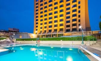 a large swimming pool is in front of a tall building with yellow lights on at Millennium Harbourview Hotel Xiamen