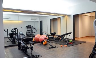 a well - equipped home gym with various exercise equipment , including a treadmill , stationary bike , and weights at Tropics Eight Suites