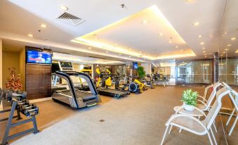 a well - equipped gym with various exercise equipment , including treadmills and stationary bikes , in a spacious room with high ceilings at City Hotel