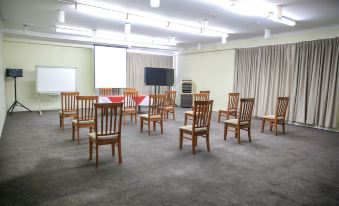 a conference room with wooden chairs arranged in rows and a tv mounted on the wall at Ryde Inn