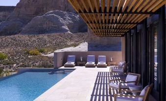 a modern swimming pool area with a wooden roof , white lounge chairs , and a clear blue swimming pool at Amangiri