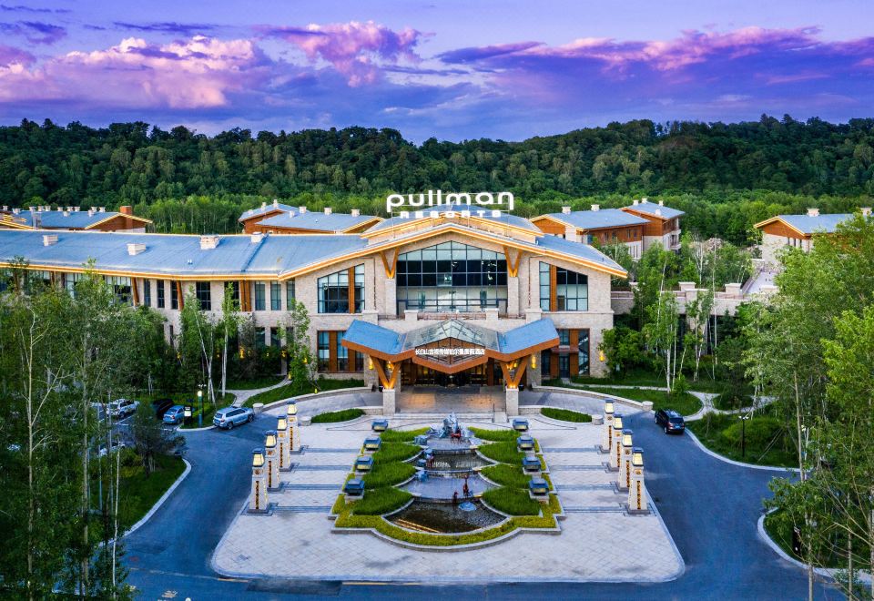 an aerial view of a large , modern building with a fountain in front of it at Pullman Changbaishan Resort