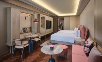 A spacious room in the middle is furnished with a bed, table, and chairs, resembling an oriental style at Blossom House Shanghai On The Bund