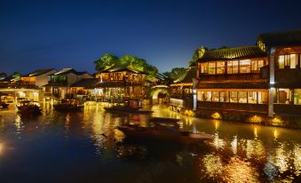 A city at night with boats on the water and buildings lining both sides at Wuzhen Huanzhu Hotel