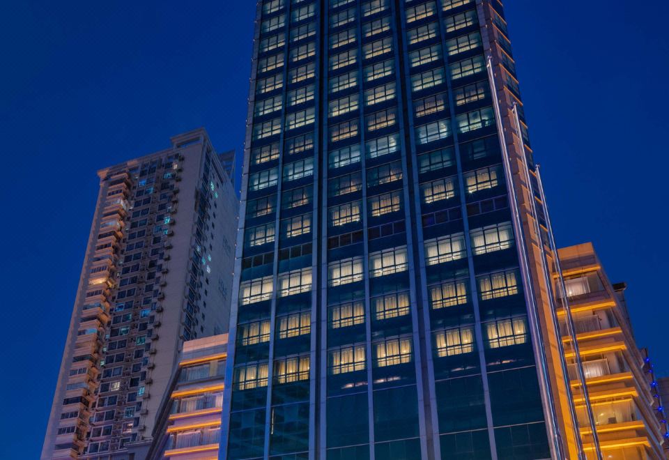 At night, there is an illuminated skyscraper in front of a large building labeled as a hotel at Metropark Jichen Hotel Shanghai