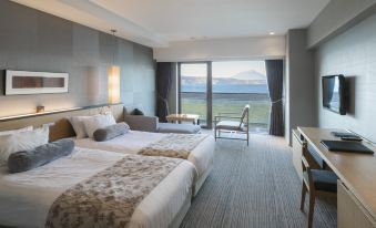a hotel room with two beds , a balcony , and a view of the ocean through the window at The Lake View Toya Nonokaze Resort