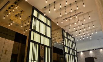 a modern restaurant with large windows and a ceiling filled with hanging lights , creating a warm and inviting atmosphere at Sem9 Senai "Formerly Known As Perth Hotel"