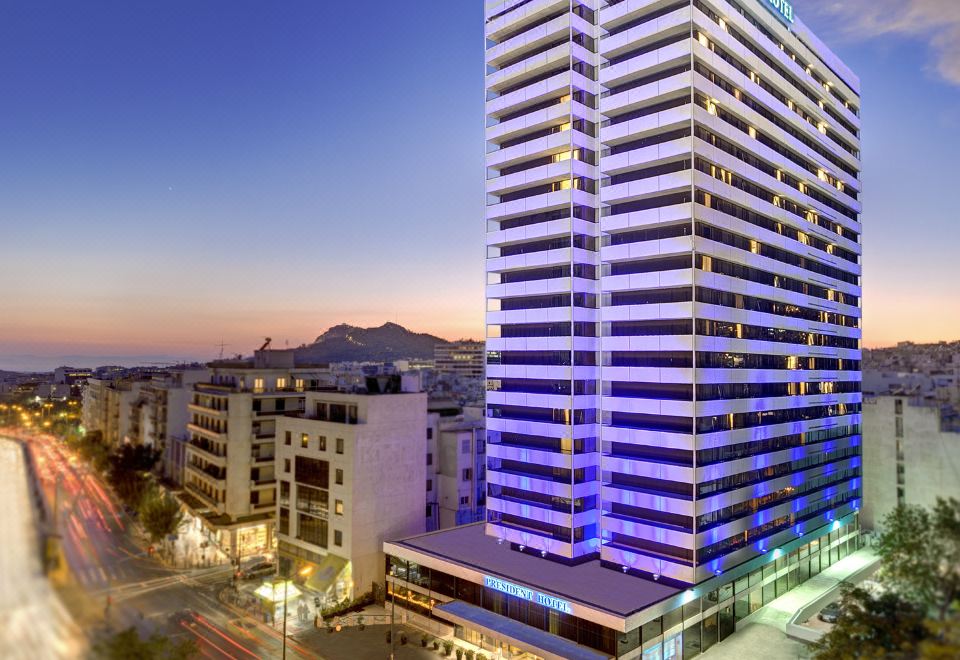 a tall , modern hotel building with blue lights is situated on a busy city street at President Hotel