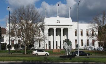 a large white building with a horse statue in front and cars parked on the street at City Edge Box Hill Apartment Hotel