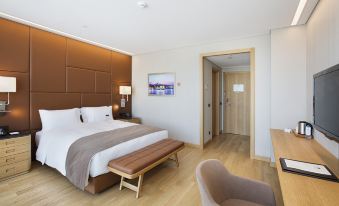a large bed with a wooden headboard and white linens is in a room with wooden floors at DoubleTree by Hilton Istanbul-Avcilar