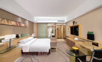 a modern hotel room with a large bed , tv , and dining table , all decorated in neutral colors at Royal Garden Hotel