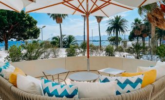 a white lounge chair with blue and white chevron cushions is under an umbrella on a patio overlooking the ocean at JW Marriott Cannes