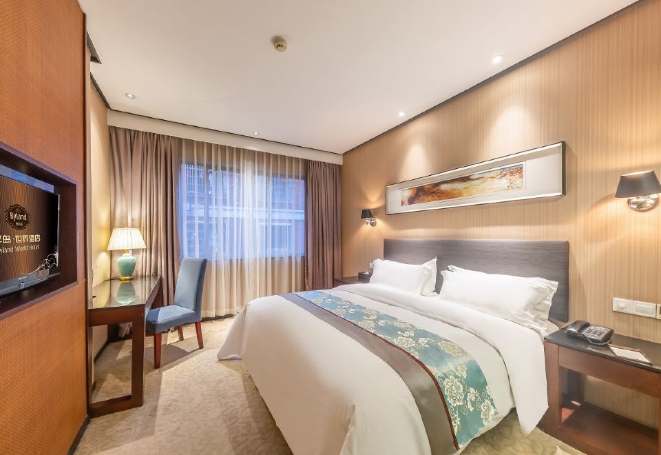 A bedroom with a large bed and a desk in the middle, along with two wall-mounted items at Byland World Hotel (Yiwu International Trade City)