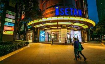 At night, a large building with pedestrians in front features an Asian restaurant entrance on its left side at CitiGO Hotel Jing'an Shanghai