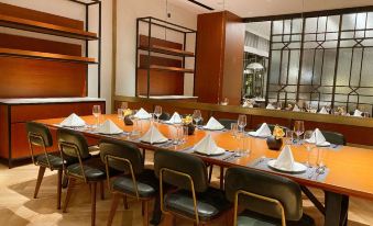 a long table set for four in the dining room of a restaurant, featuring large wooden chairs at Hilton Garden Inn Guangzhou Tianhe