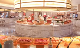 There is a spacious room with tables and chairs, and next to the counter, there is an indoor food display at Yindu Hotel