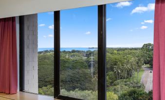 a room with a large window overlooking a beautiful view of the ocean and trees at Frontier Hotel Darwin
