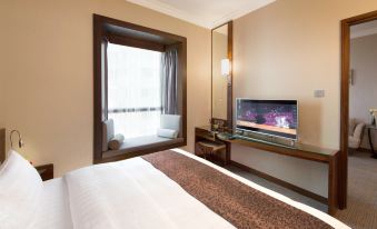 A spacious bedroom with a large bed and a flat-screen TV mounted on the wall at Rosedale Hotel Hong Kong