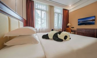 a large bed with a stuffed panda on it , surrounded by various items in the room at Panda Hotel
