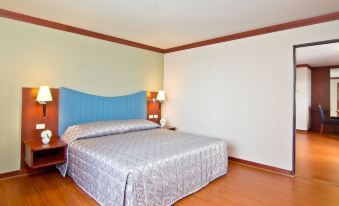 There is a large bed with hardwood floors and a wood-paneled headboard in the middle room at Baiyoke Suite Hotel