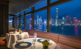 a table in the dining room with large windows overlooking the city at night and another view from at Marco Polo Hongkong Hotel