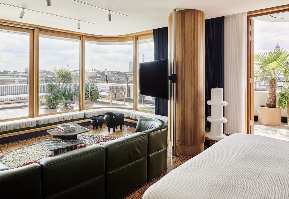 a modern hotel room with a large bed , green leather couch , and a flat - screen tv at The Standard London