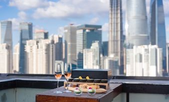 A table on an elevated balcony in front, offering a view of the city, is set with food and drinks at Hotel Indigo Shanghai on The Bund