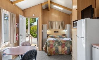 a cozy bedroom with a bed , desk , and chairs , as well as an open door leading to a balcony at Discovery Parks - Jindabyne