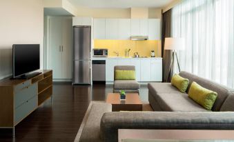 a modern living room with a gray couch , wooden coffee table , and a kitchen area at Element Vancouver Metrotown