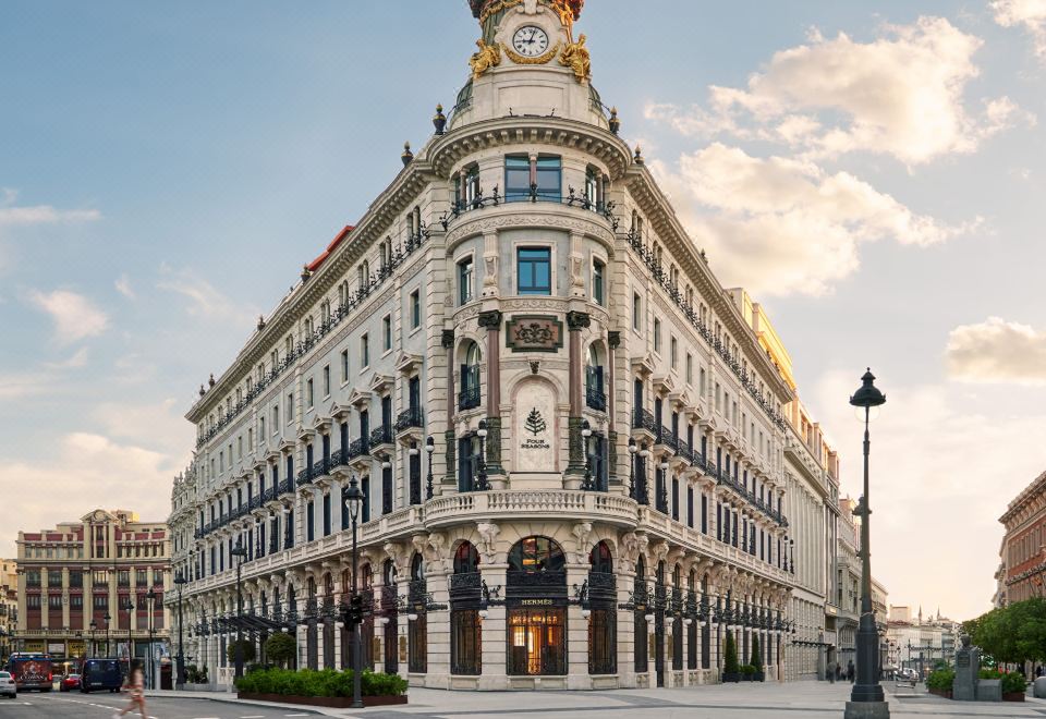 a large white building with a clock on the top , situated on a street corner at Four Seasons Hotel Madrid