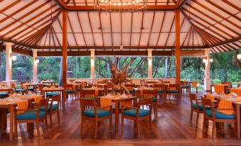 a dining room with wooden tables and chairs arranged for a group of people to enjoy a meal together at Adaaran Select Meedhupparu - with 24Hrs Premium All Inclusive