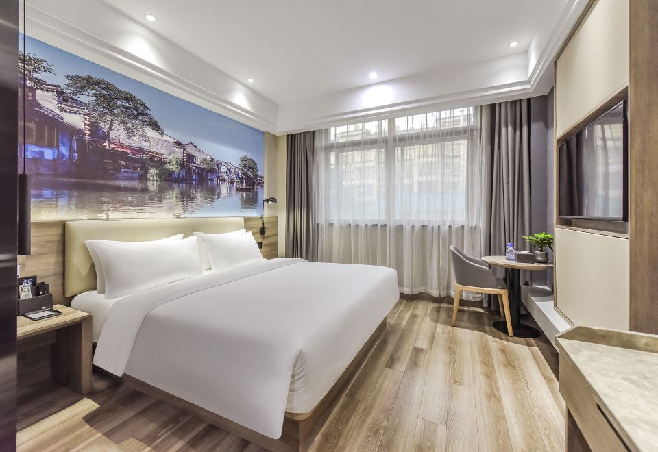 The modern bedroom features a double bed and a large window that overlooks the pool area at Jinhao International Hotel