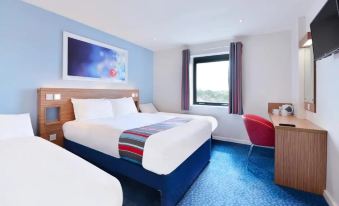 a hotel room with two beds , one on the left and one on the right side of the room at Travelodge Slough