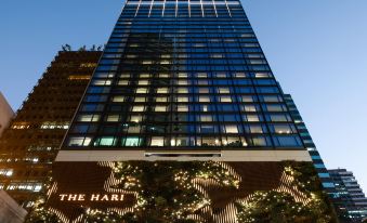 "At night, there is a tall building illuminated with lights and the word ""hotel"" displayed above it" at The Hari Hong Kong