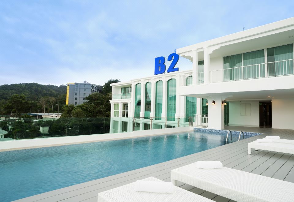 The apartment complex has a large white and brown colored building with a swimming pool in front at B2 Phuket Premier Hotel