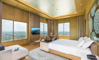 a modern bedroom with a large bed , a flat - screen tv mounted on the wall , and a beautiful view of the city at Alila Solo