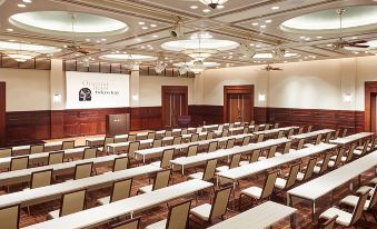 a large conference room with rows of chairs and a podium in the front , facing a projector screen at Oriental Hotel Tokyo Bay