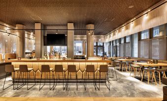 a modern bar area with wooden furniture , including chairs and tables , arranged in an open space at HYPERION Hotel Leipzig